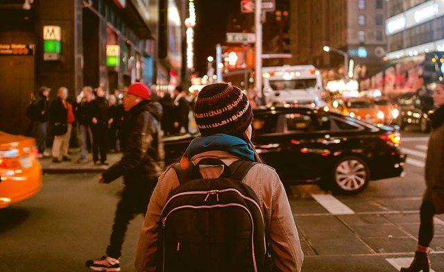A girl with a backpack stands facing a busy intersection
